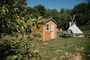 una pequeña casa de madera en un campo con una tienda de campaña en Spellbound Farm en Union