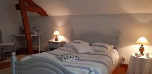 a bedroom with a white bed with two tables and two lamps at Nuit Champenoise Tout Confort in Louze