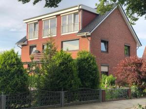 a red brick house with a black fence at Ferienwohnung Nordlichter Bremerhaven in Bremerhaven