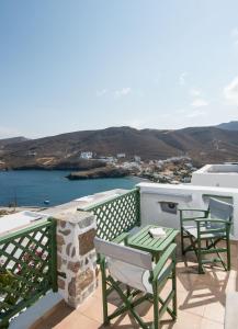 a balcony with chairs and tables and a view of the ocean at Kalderimi Traditional Houses in Astypalaia