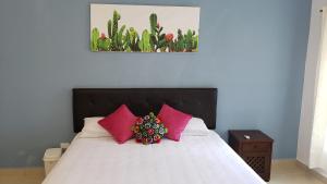 - une chambre avec un lit et des oreillers roses dans l'établissement Studios at Main Park Cozumel, à Cozumel