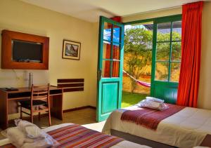 a bedroom with two beds and a desk and a window at Hotel Tartar in Cajamarca