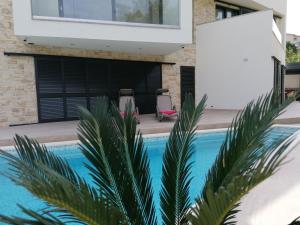 a house with a swimming pool with two chairs at Villa NOVAMARIN - heated pool, sauna, garden in Drage