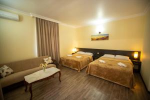 a hotel room with two beds and a couch at Hotel Chveni Ezo in Kobuleti