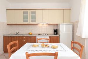 a kitchen with a table and chairs and a refrigerator at Apartmani Tamara in Sveti Anton