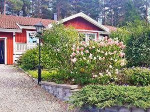 ein Haus mit einem roten Gebäude und rosa Blumen in der Unterkunft Holiday home VäTö in Harg