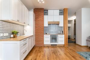a kitchen with white cabinets and a brick wall at Lossi Old Town Apartment in Tartu +9 photos