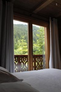 Les AlluesにあるChalet Les 5 Sapinsのベッドと大きな窓のある寝室