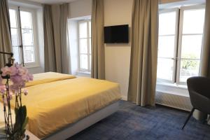 - une chambre dotée d'un lit avec des draps jaunes et des fenêtres dans l'établissement Boutique Hôtel de l'Ecu Vaudois, à Begnins