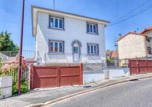 a white house with a red fence on a street at COCON de DOUCEUR entre DISNEY et PARIS in Villiers-sur-Marne +1 photo
