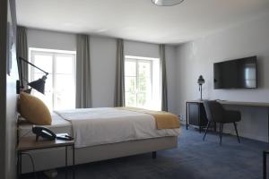 a bedroom with a bed and a desk and a television at Boutique Hôtel de l'Ecu Vaudois in Begnins
