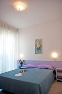 Un dormitorio con una cama azul con almohadas moradas en Hotel Aurea, en Bellaria-Igea Marina