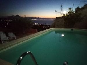 a swimming pool with a view of the ocean at night at Villa Verde in Cefalù