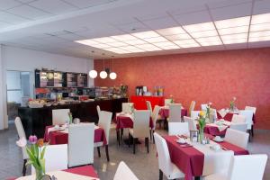 un restaurante con mesas, sillas blancas y una barra en Trip Inn Goethe Business Messe, en Frankfurt
