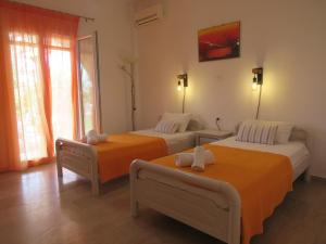 twee bedden in een kamer met oranje lakens bij Biscoutsis Apartments & Studios in Kavos