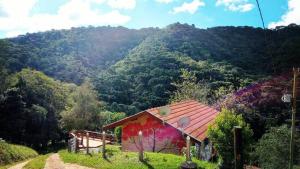 a house with a red roof in front of a mountain at Sonho na Serra Chalé 1 in Gonçalves