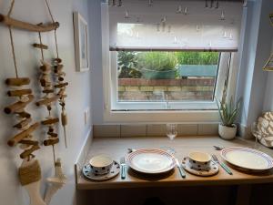 a table with plates and glasses and a window at Tiny Beach House in Saint Annes on the Sea