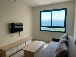 ein Wohnzimmer mit einem Sofa und einem Flachbild-TV in der Unterkunft On The Lake in Tiberias