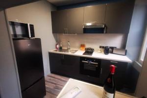 - une cuisine avec des armoires noires et un réfrigérateur noir dans l'établissement Au numéro 4 (le Flex), à Châteauroux