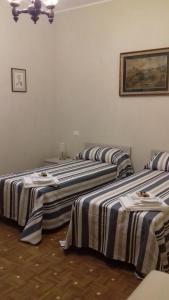 three beds in a room with striped sheets at LOCANDA CAVALLO BIANCO - AFFITTACAMERE in Robella