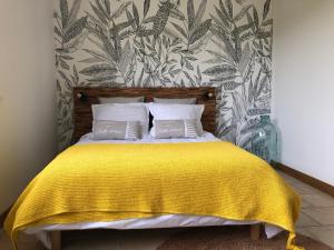 um quarto com uma cama com um cobertor amarelo em Jardin des Pérelles em Varengeville-sur-Mer