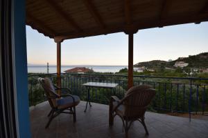 a balcony with chairs and a table and the ocean at Elena's Family Apartments in Leonidio