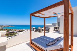 a bedroom with a bed on a balcony with the ocean at Minois Boutique Hotel in Stalida