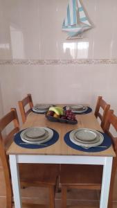 a table with plates and a bowl of fruit on it at Casa na Costa in Costa Nova