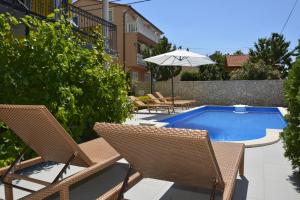 a swimming pool with two chairs and an umbrella at Apartment MARO in Senj