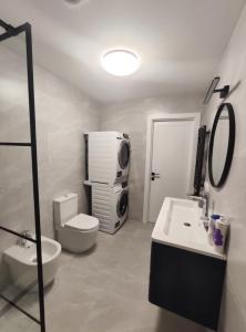 a bathroom with a sink and a toilet and a tv at SEA GATE APARTMENT 20th floor in Klaipėda