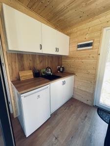 a kitchen with white cabinets and a wooden wall at Neverland in Zelwa