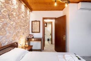 Un dormitorio con una cama y una pared de piedra. en Villa Yiannitsis - Sunset by the Sea, Acharavi Beach, en Acharavi