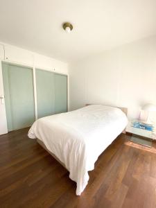 a bedroom with a white bed and a wooden floor at Superb Apartment In Cannes With Magnificent View ! in Cannes