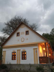Una gran casa blanca con un reloj. en Kiscsermely Vendégház, en Jósvafő