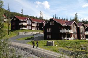 two people walking down a dirt road in front of a building at Höglekardalens Semesterby - Bydalsfjällen in Bydalen