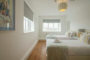 deux lits dans une chambre aux murs blancs et au parquet dans l'établissement The Eyre Square Townhouse, à Galway