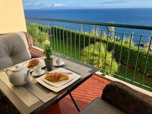 een tafel met croissants op een balkon met uitzicht op de oceaan bij Oceanic Apartment in Caniço