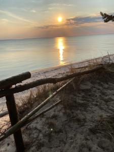 a sunset on the beach with a wooden fence at Przyczepa Abordaż na Campingu Kormoran in Hel