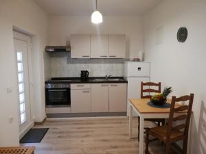 eine Küche mit weißen Schränken, einem Tisch und einem Esszimmer in der Unterkunft Apartments Maks in Kraljevica