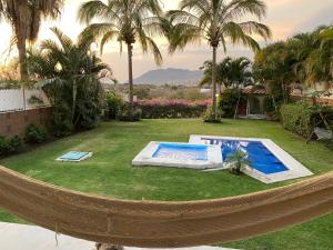 a hammock in a backyard with a swimming pool at Casa de las Palmeras Lomas de Cocoyoc in Atlatlahucan