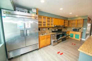 uma cozinha com um frigorífico de aço inoxidável e armários de madeira em California Dreams Hostel - Ocean Beach em San Diego