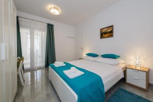 a bedroom with a large bed with blue pillows at Apartmani Ujakovic in Kaštela