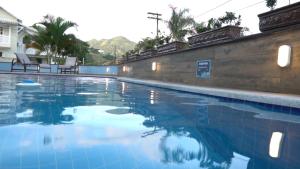 uma piscina com água azul em frente a um edifício em Flats Catamarã em Angra dos Reis