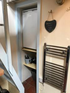 a stairway leading up to a kitchen with a refrigerator at Bwthyn Bach Fishermans Cottage in Barmouth