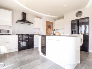 a kitchen with white cabinets and black appliances at Summerhayes in Redruth