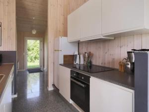 una cocina con armarios blancos y un aparato negro en 6 person holiday home in H rve, en Hørve