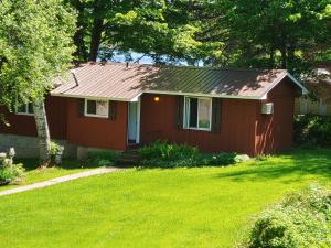 una pequeña casa roja con un patio de césped en Lakeshore Motel Ice Lake en Iron River