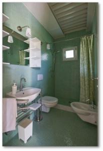 a green bathroom with a sink and a toilet at Casali Romei in Sarzana