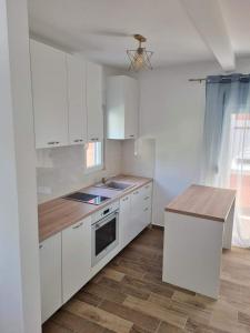 uma cozinha com armários brancos e um balcão de madeira em Apartmani Vanja em Baošići