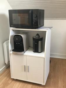 a white cabinet with a microwave on top of it at Appartement T2 meublé in Saint-Quentin